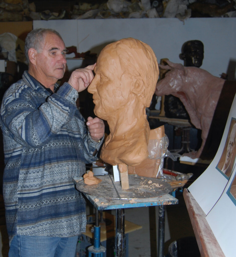 Western Australian sculptor, Robert C Hitchcock, at his studio working on an over-life-sized clay portrait bust.