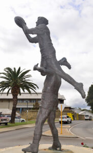 Bronze statue of a rugby player lifting a teammate to catch a ball. Sculptor - Robert C Hitchcock
