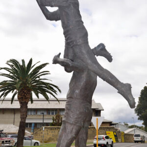Bronze statue of a rugby player lifting a teammate to catch a ball. Sculptor - Robert C Hitchcock