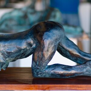 Bronze sculpture of a crawling figure displayed on a wooden base. Sculptor - Robert C Hitchcock