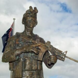 Bronze sculpture of a soldier with a rifle, set against a cloudy sky with flags in the background. Sculptor - Robert C Hitchcock