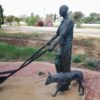 A statue of a man with a shovel and a dog showcased in a gallery.