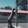 Bronze sculpture of a figure holding a pole in an outdoor setting. Sculptor - Robert C Hitchcock