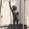 Bronze sculpture of a young male figure holding a spear, displayed in sunlight with a building backdrop. Sculptor - Robert C Hitchcock